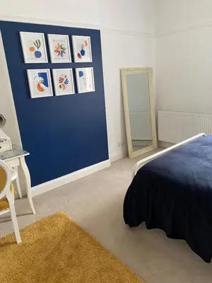 a bedroom with a blue wall with a bed and a mirror at Caerlaverock Cottage in Prestwick
