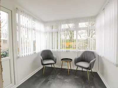two chairs and a table in a room with windows at Largieholm in Mauchline