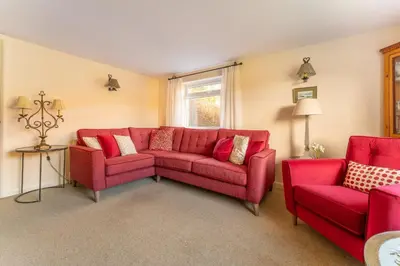 a living room with a red couch and two chairs at Le Tholonet in Grasmere