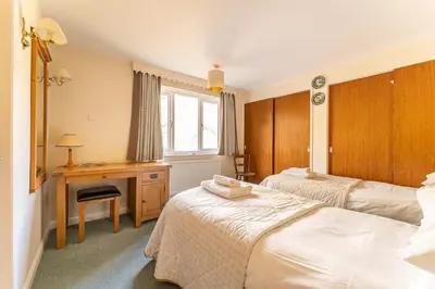 a bedroom with two beds and a desk and a window at Le Tholonet in Grasmere