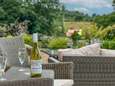 a bottle of wine sitting on a table with glasses at High House Cottage, Southwaite in a rural setting with garden, BBQ & hot tub in Southwaite