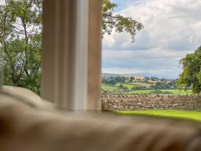 a window with a view of a stone wall at High House Cottage, Southwaite in a rural setting with garden, BBQ & hot tub in Southwaite