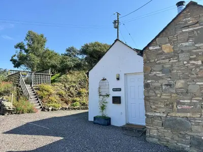 a small white garage with a stone wall at Birds Nest in Gatehouse of Fleet