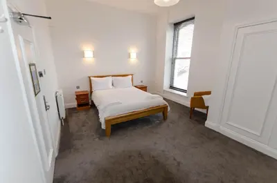 a white bedroom with a bed and a window at Opul Boutique at Admiral House in Douglas