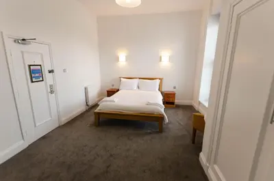 a small bedroom with a bed and a door at Opul Boutique at Admiral House in Douglas