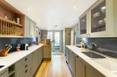 a large kitchen with white cabinets and wooden floors at Poet's Corner in Grasmere