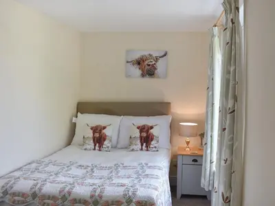a bedroom with a bed with two dogs on the pillows at The Stables in Beckfoot