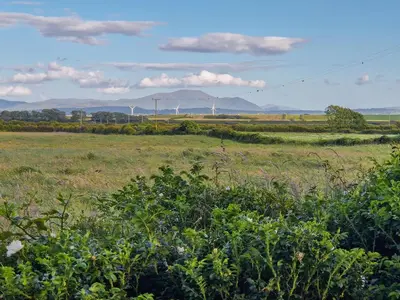 a green field with wind turbines in the distance at The Stables in Beckfoot