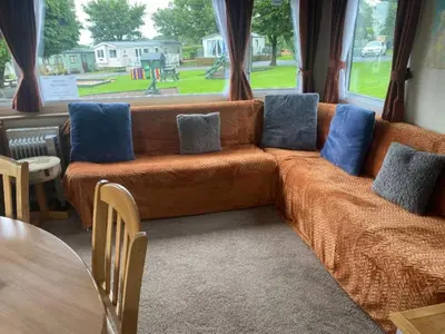 an orange couch with blue pillows in a living room at 23 The Beeches in Gilcrux