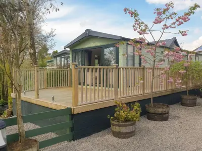 a house with a wooden deck and some plants at Stream Side View in Lamplugh