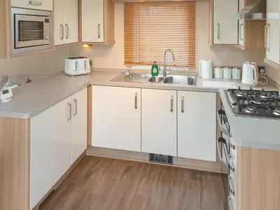 a kitchen with white cabinets and a sink at Stream Side View in Lamplugh