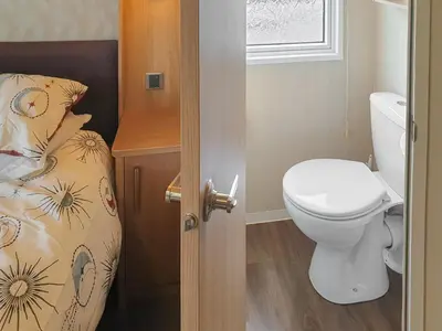 a small bathroom with a toilet and a bed at Stream Side View in Lamplugh