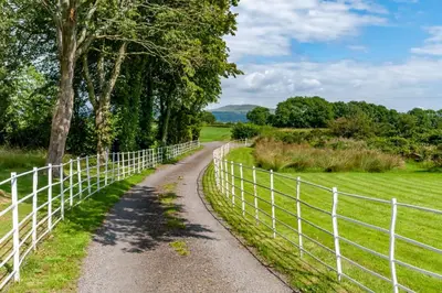 a gravel road next to a white fence at Courtyard Cottages Granary Cottage in Wigtown