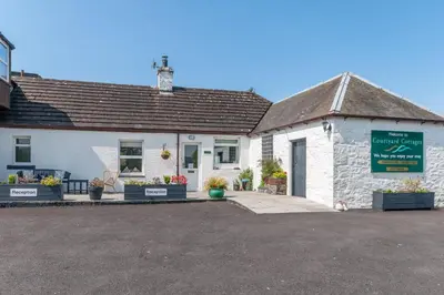 a white building with a sign in front of it at Courtyard Cottages Granary Cottage in Wigtown