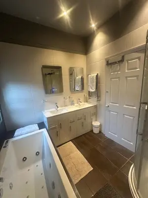 a bathroom with a tub and a sink and a toilet at The hot tub by the waterfall - facilities included in Lower Foxdale