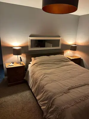 a bedroom with a bed and two night stands with lamps at The hot tub by the waterfall - facilities included in Lower Foxdale