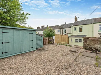 a backyard with a blue garage and some houses at 2 Bed in Arlecdon 95126 in Arlecdon