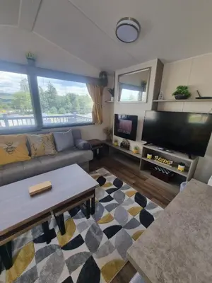 a living room with a couch and a flat screen tv at Luxury static caravan in Beattock