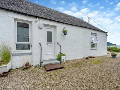a white house with a door and a window at Carraig Dhubh Cottage - Uk47123 in Whiting Bay
