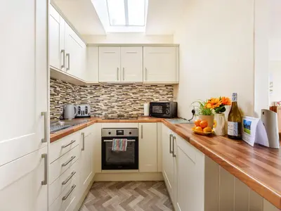 a kitchen with white cabinets and a wooden counter top at Carraig Dhubh Cottage - Uk47123 in Whiting Bay