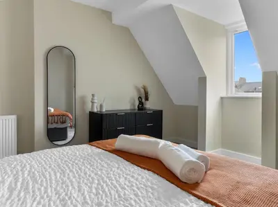 a bedroom with a white bed with a large mirror at The Penthouse - Crosby St 2 Bed in Maryport