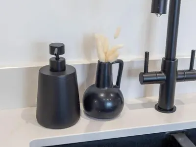 two black bottles sitting on a counter next to a sink at The Penthouse - Crosby St 2 Bed in Maryport