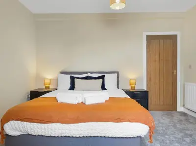 a bedroom with a large bed with an orange blanket at The Penthouse - Crosby St 2 Bed in Maryport