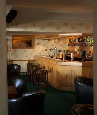 a bar in a restaurant with a bunch of chairs at Patterdale Hotel in Patterdale