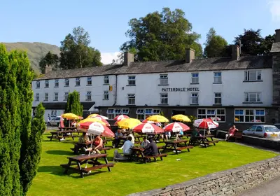 a group of people sitting at tables with umbrellas at Patterdale Hotel in Patterdale