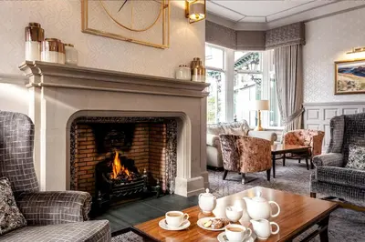 a living room with a fireplace and a table at The Inn On The Lake in Glenridding