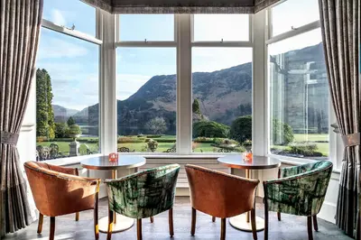 a room with two tables and chairs and a large window at The Inn On The Lake in Glenridding