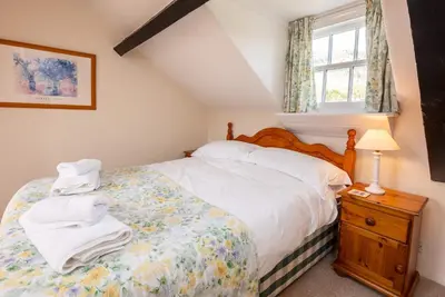 a bedroom with a bed with white sheets and a window at Myrtle Cottage in Chapel Stile