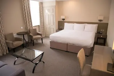 a hotel room with a bed and a table and chairs at Crown & Mitre Hotel in Carlisle
