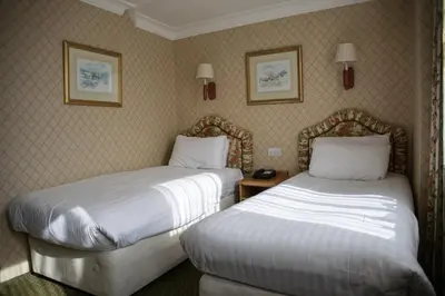 a hotel room with two beds and two pictures on the wall at Crown & Mitre Hotel in Carlisle