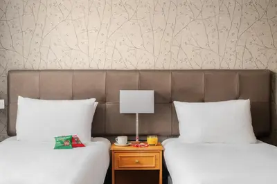 two beds with white pillows and a table with a lamp at The County Hotel in Carlisle