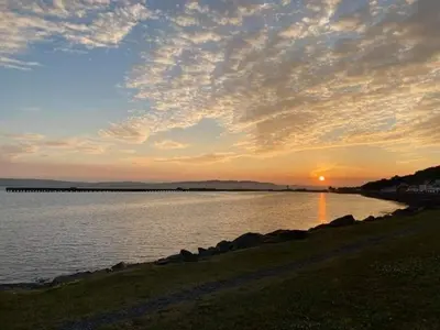 a sunset over a body of water with the sun setting at Static Caravan situated at Wigbay, Stranraer in Stranraer