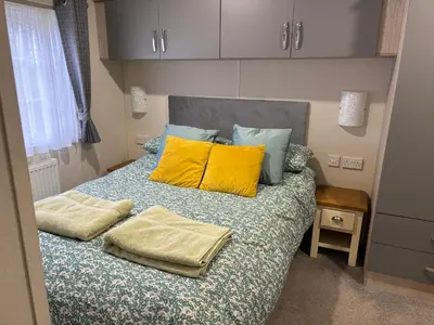 a bedroom with a bed with two yellow pillows at Forestbrook - Cheerful two bedroom tiny house in Carlisle