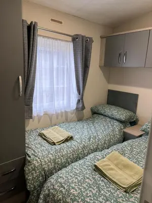two beds in a small room with a window at Forestbrook - Cheerful two bedroom tiny house in Carlisle