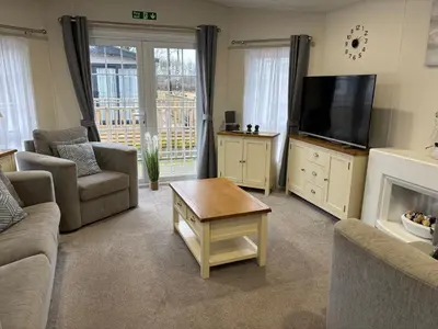 a living room with a tv and a couch and a table at Forestbrook - Cheerful two bedroom tiny house in Carlisle