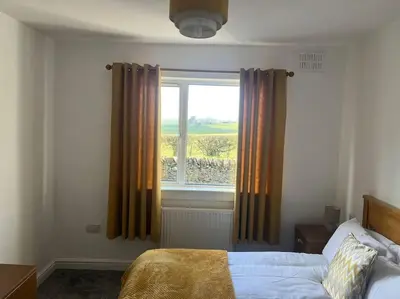 a bedroom with a bed and a window at Barnbackle Cottage in Shawhead