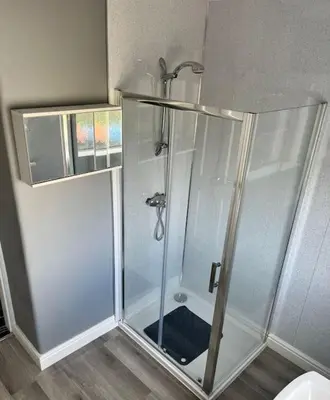a shower with a glass door in a bathroom at Barnbackle Cottage in Shawhead