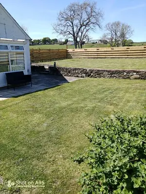 a yard with a bench next to a house at Barnbackle Cottage in Shawhead