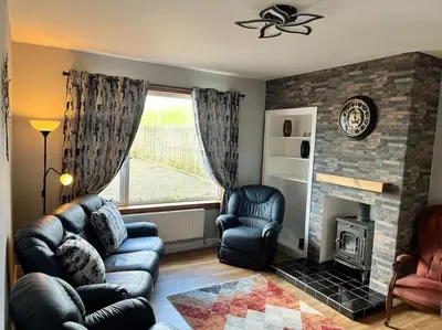 a living room with a couch and chairs and a fireplace at Barnbackle Cottage in Shawhead