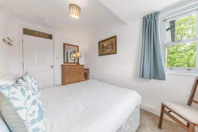 a white bedroom with a bed and a window at The Hytte, 19 Greta Grove House in Keswick