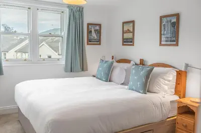 a bedroom with a large white bed with blue pillows at The Hytte, 19 Greta Grove House in Keswick