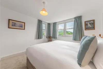 a bedroom with a large white bed and windows at The Hytte, 19 Greta Grove House in Keswick
