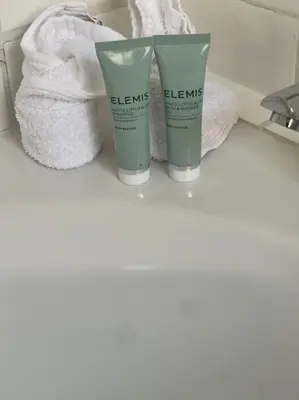two bottles of elms on a bathroom counter with towels at Birks road in Cleator Moor