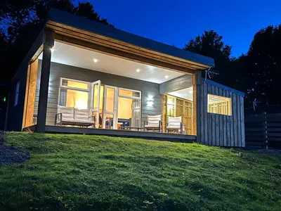 a small house with a large deck at night at Castle Glen Lodge in Dumfries