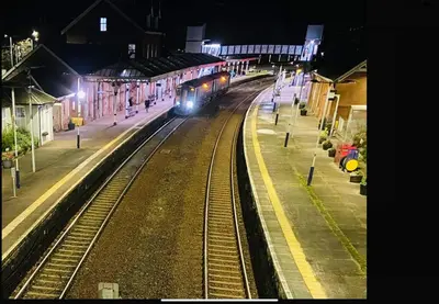 a train on the tracks at a train station at night at Castle Glen Lodge in Dumfries