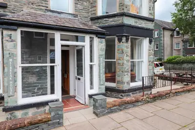 a stone house with a white door and windows at Melbreak House 2 in Keswick